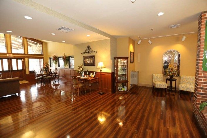A spacious living room with polished wood flooring, elegant furniture, and decorative elements.