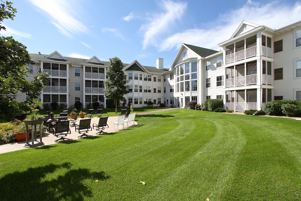 A view of a residential apartment complex with a well-maintained lawn and outdoor seating area.