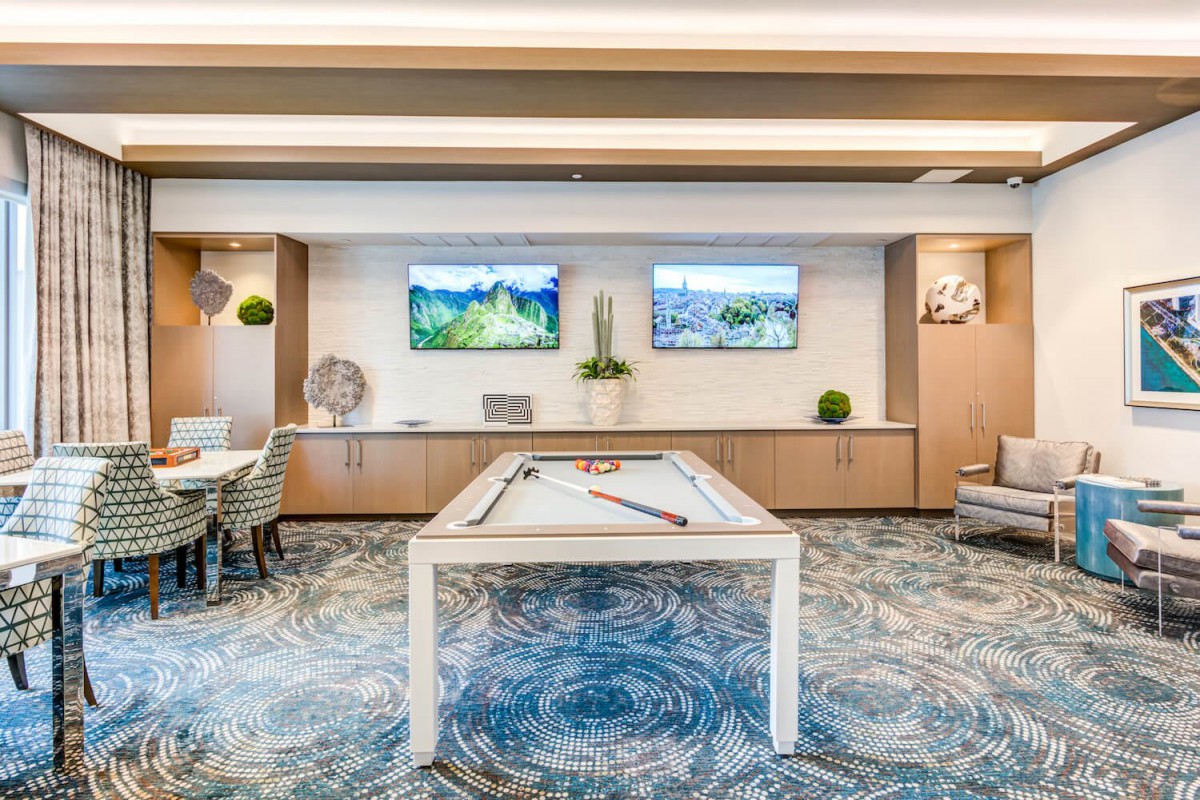 A modern game room featuring a pool table and two wall-mounted televisions.