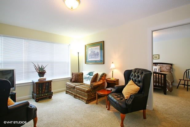 A cozy living room with elegant armchairs, a sofa, and warm lighting.