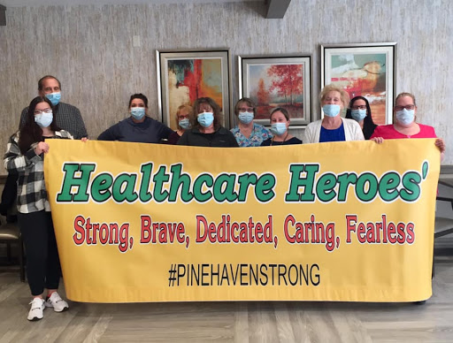 A group of healthcare professionals proudly displaying a banner honoring their dedication and bravery.