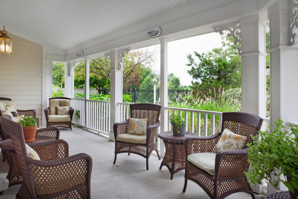 A cozy porch with wicker furniture offers a relaxing garden view.