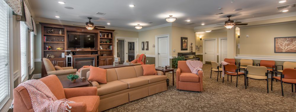 A cozy living room featuring a sofa, armchairs, and a bookshelf.