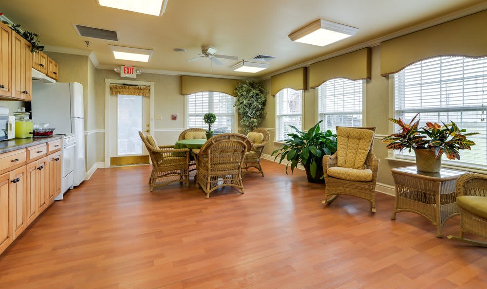 A cozy living room with wicker furniture, large windows, and potted plants.
