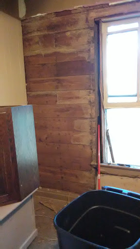 A view of a room featuring wooden paneling and a window, indicative of ongoing renovations.