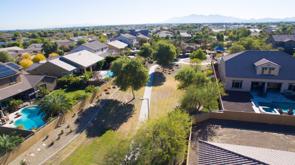 A scenic aerial view of a suburban neighborhood with houses, trees, and a pathway.