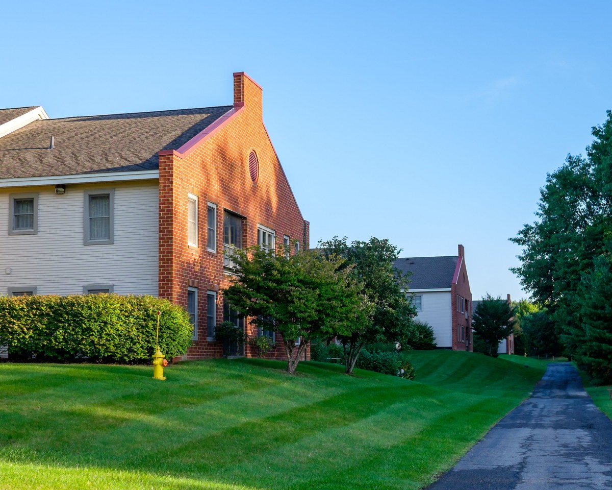 A suburban house with a well-maintained lawn and trees at sunset.