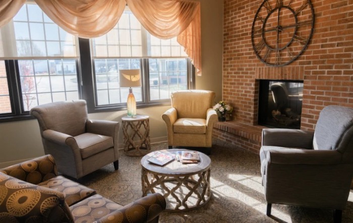 A cozy living room with comfortable seating, a fireplace, and ample natural light streaming in through the windows.