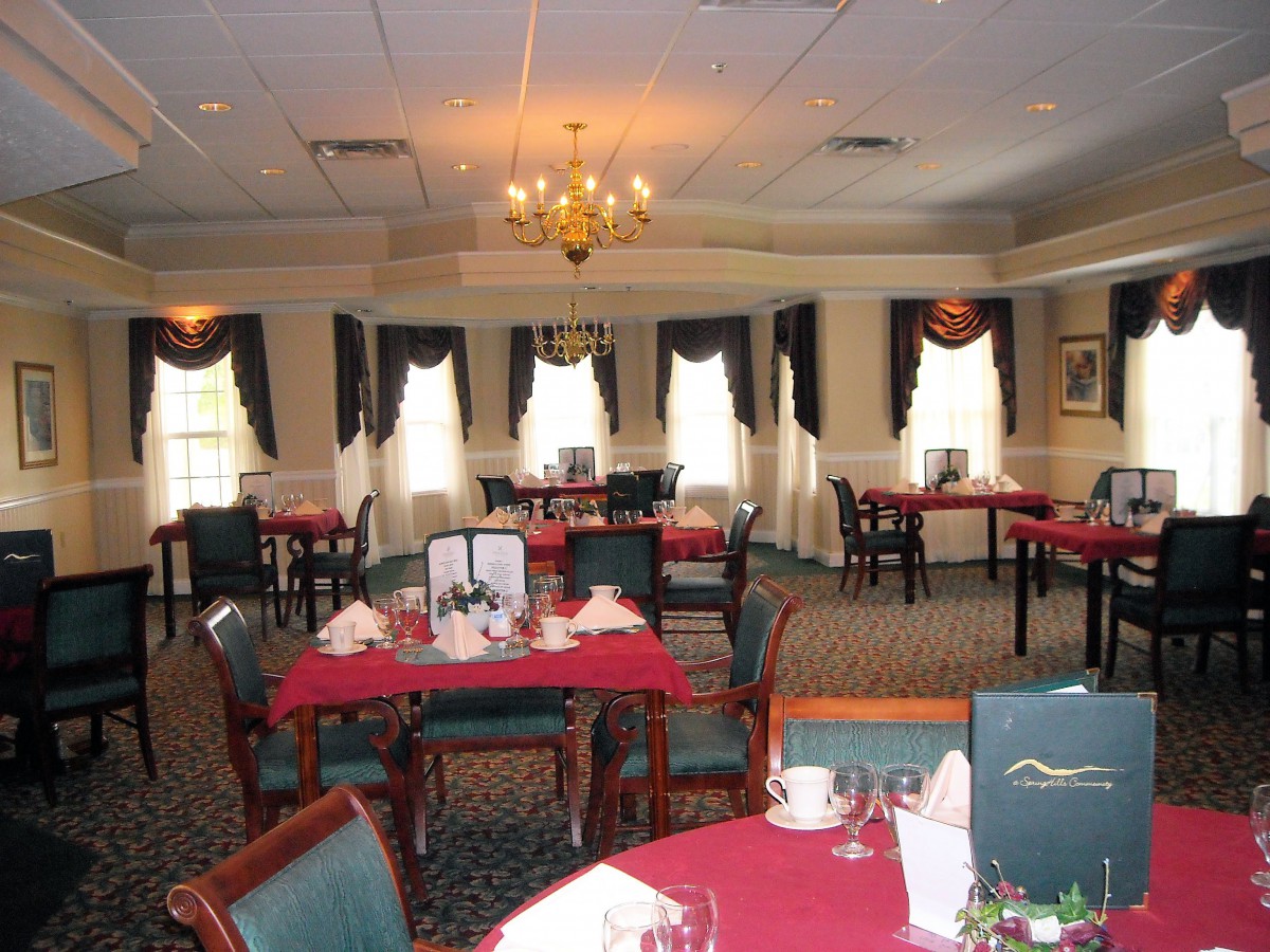 An elegantly set dining room with red tablecloths and neatly arranged furniture.
