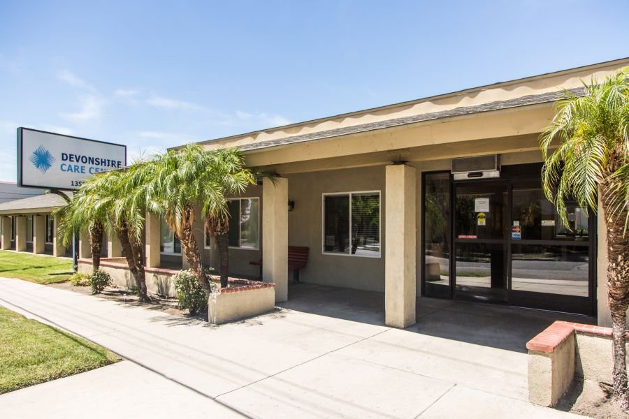 A commercial building entrance with palm trees and glass doors.