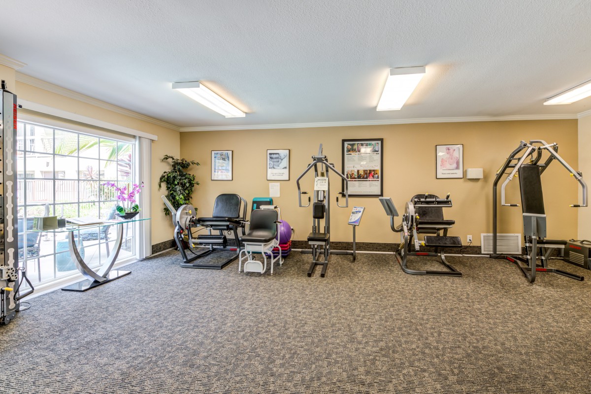 A small gym with various exercise equipment and posters on the walls.