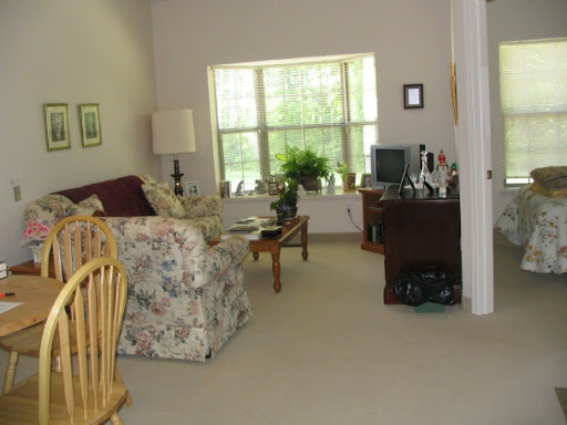 A cozy living room with floral sofa, desk area, and a view of greenery outside.
