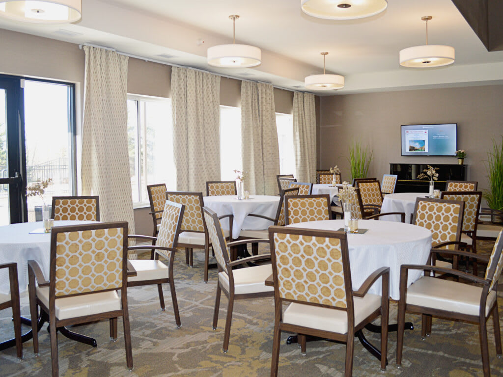 A well-lit dining room with neatly arranged tables and chairs, featuring elegant interior design elements.