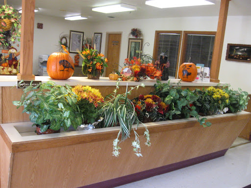 A vibrant autumn display featuring pumpkins and a variety of flowers indoors.
