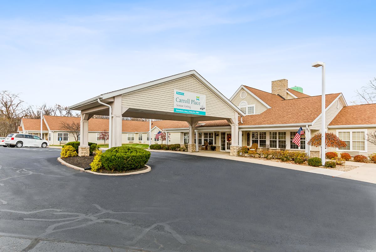 The entrance to a hotel with a covered driveway and landscaped surroundings.