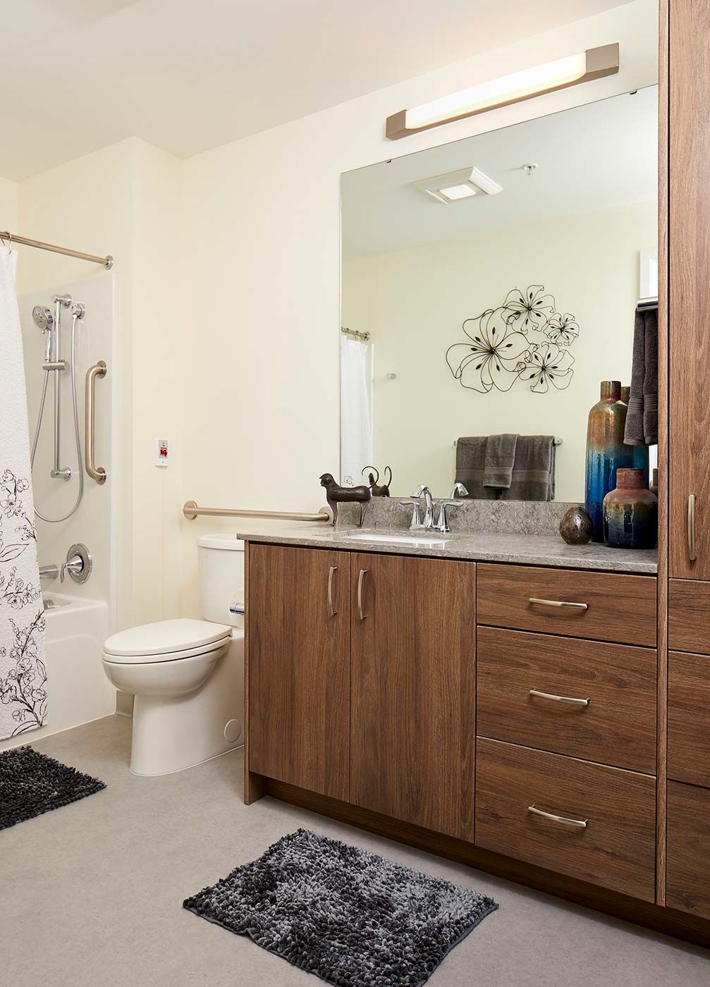 A modern bathroom featuring wooden cabinets, a large mirror, and elegant decor.