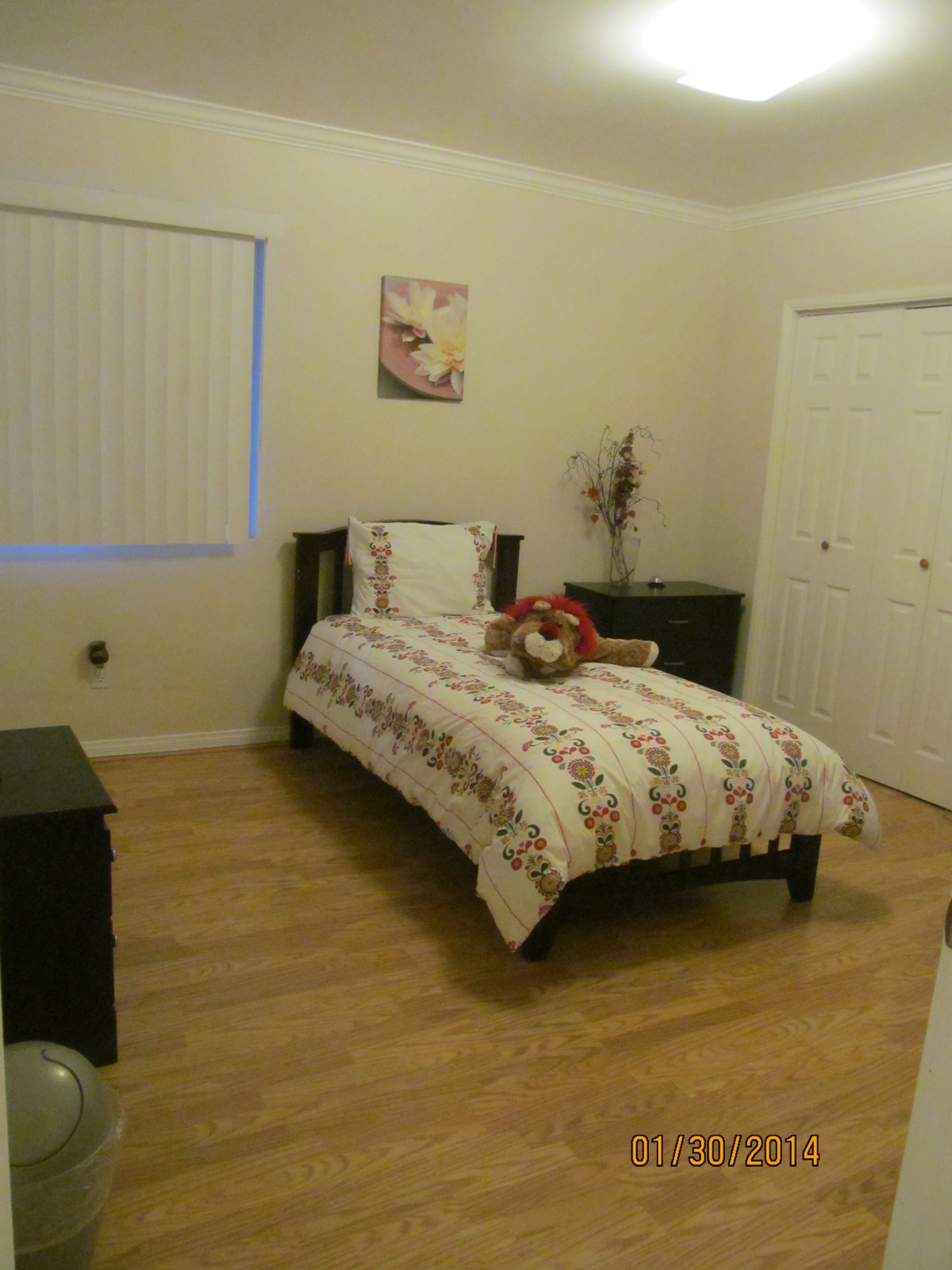 A cozy bedroom with a single bed, wooden flooring, and simple decor.
