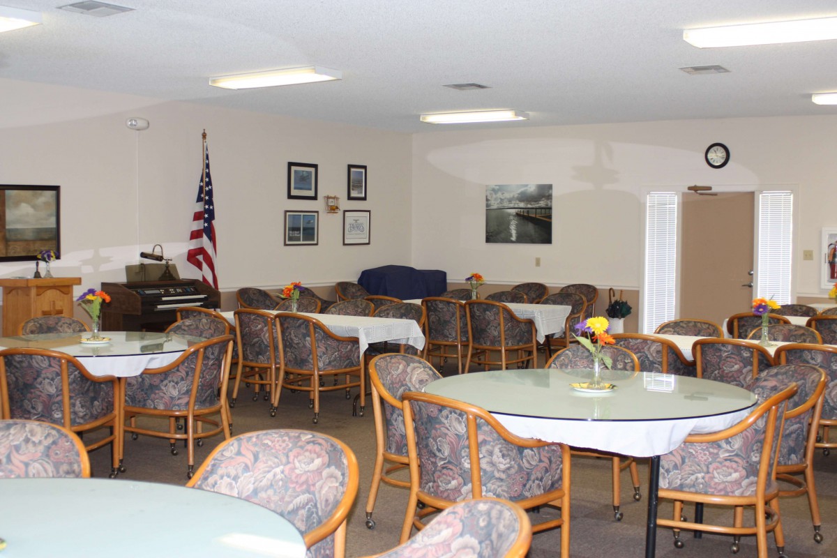 A quiet dining area with multiple tables and chairs, decorated with an American flag and framed pictures on the wall.