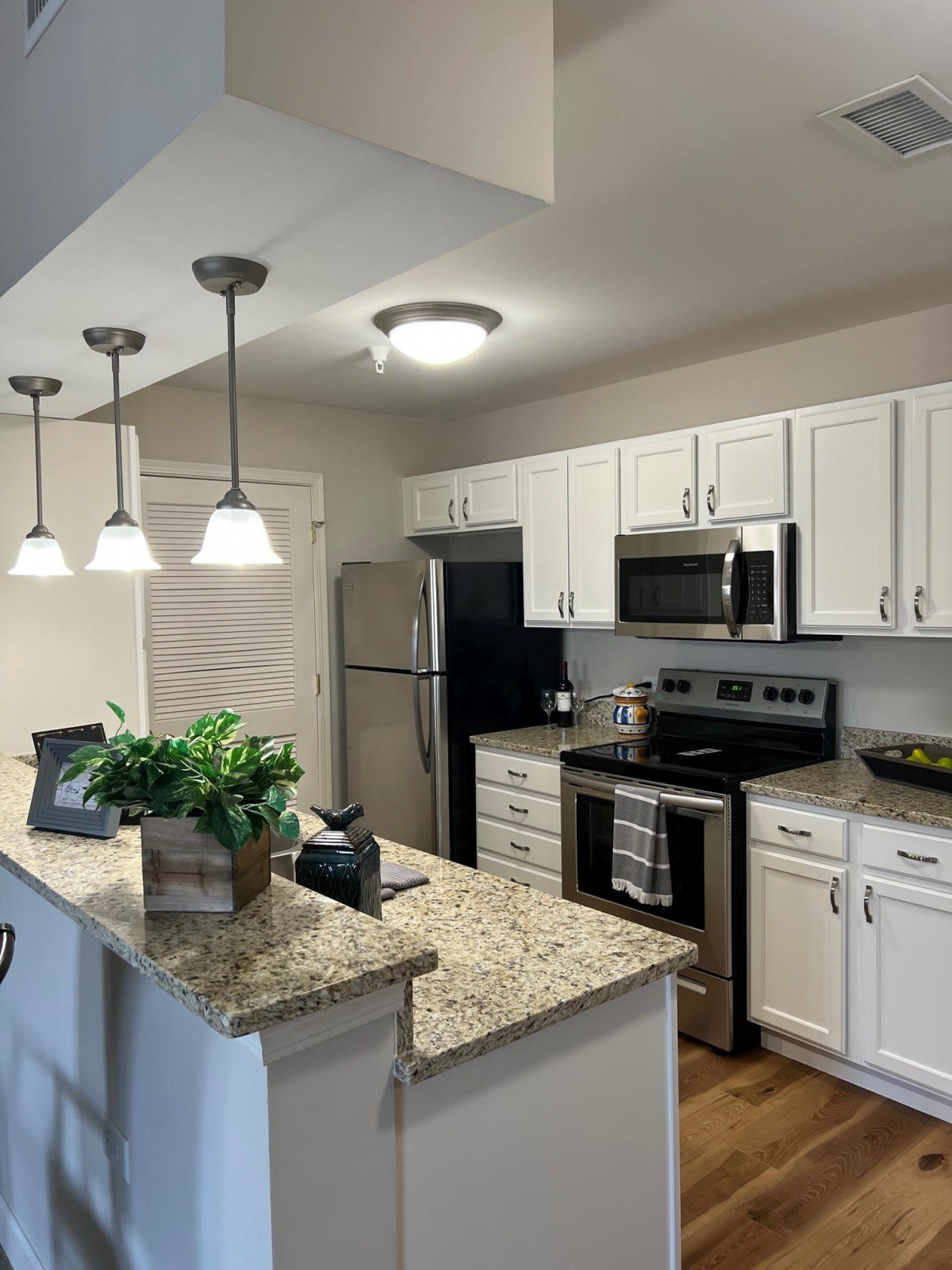 A modern kitchen with white cabinets, granite countertops, and stainless steel appliances.