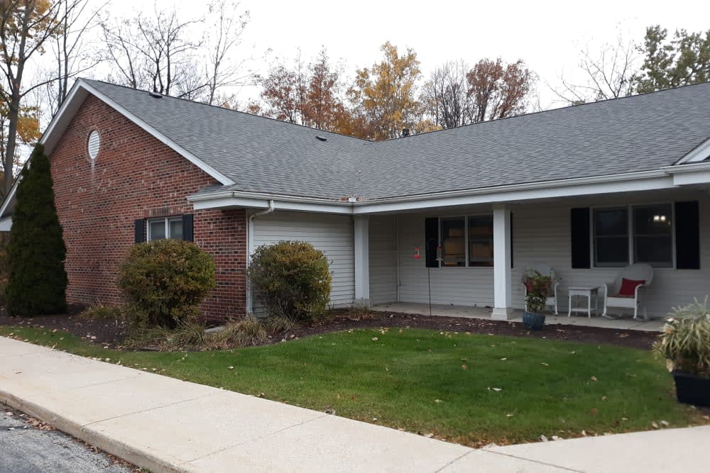 A suburban house with a brick facade, surrounded by a neat lawn and autumn trees.