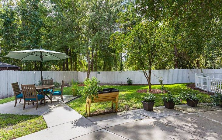 A tranquil backyard with a garden and patio area under the sunny sky.