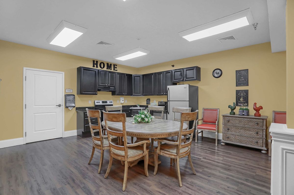 A cozy kitchen and dining area featuring a round table and chairs, with black cabinets and a refrigerator.