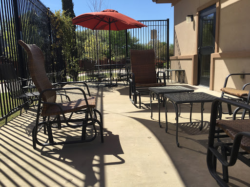 A sunny outdoor patio area featuring lounge chairs and an umbrella.