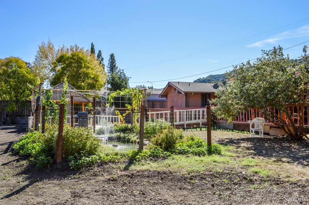 A rustic house with a garden and fence in a rural setting.