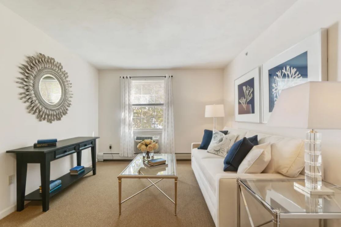 A modern and elegantly decorated living room featuring a comfortable sofa, stylish mirror, and contemporary artwork.