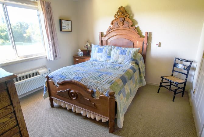 A cozy bedroom featuring an antique wooden bed with a decorative headboard and a patchwork quilt.