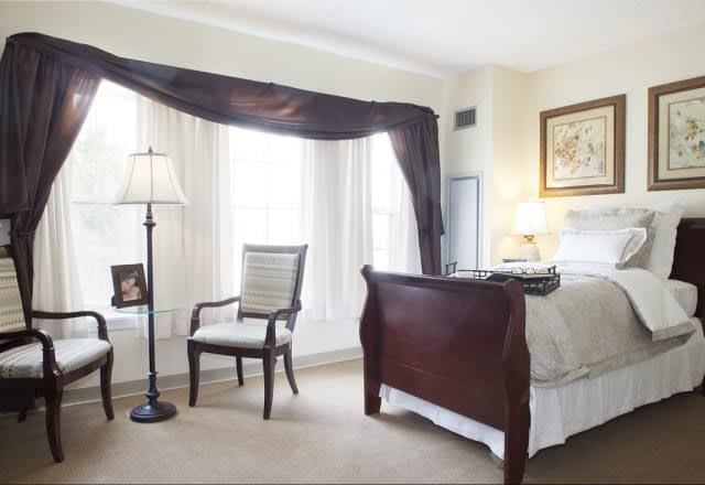 A cozy bedroom with elegant furniture and natural light streaming through the window.