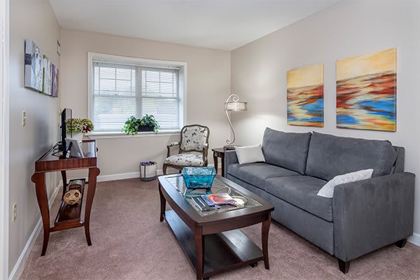 A cozy living room with a sofa, coffee table, and artwork on the wall.