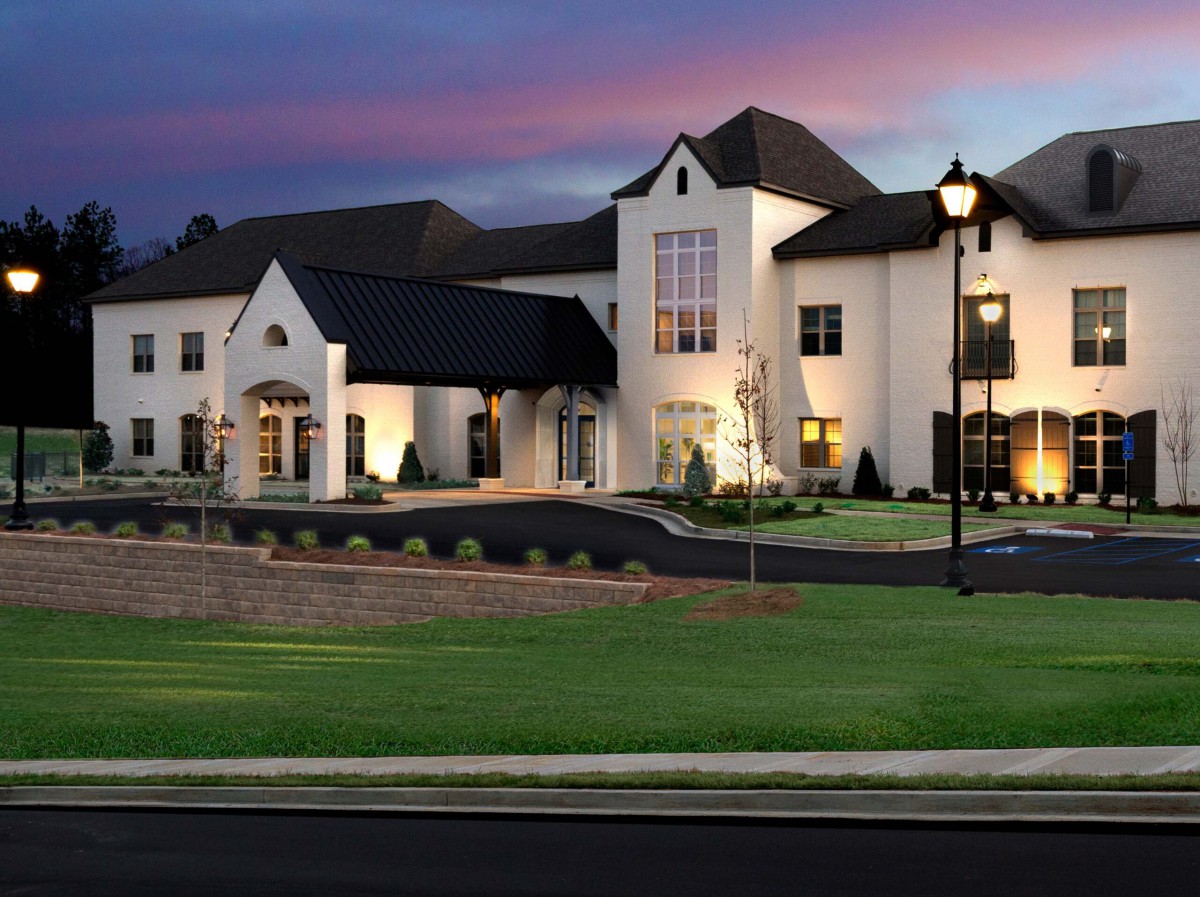 A luxurious mansion illuminated at dusk with elegant landscape lighting.