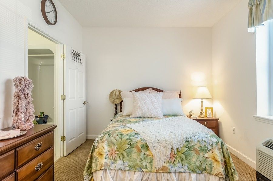 A cozy bedroom with a bed adorned with floral bedding and a lamp on the nightstand.