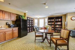 A cozy library space with bookshelves, tables, and chairs for reading.