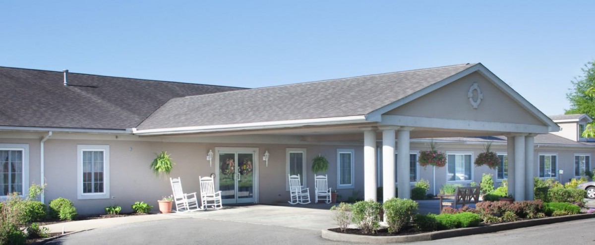 A building with a front porch featuring rocking chairs and columns.
