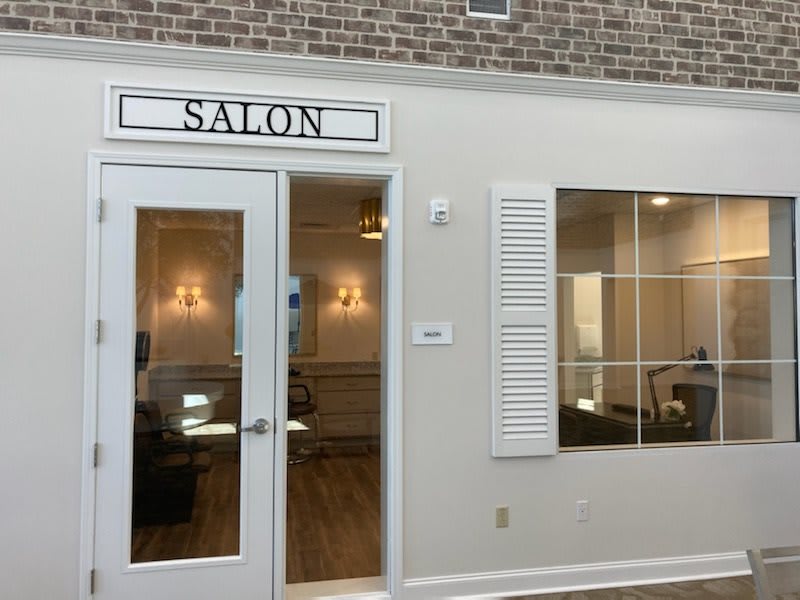 A salon entrance with glass doors and a large window pane.