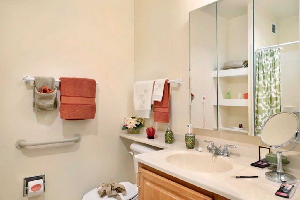 A modern bathroom with a sink, mirror, and neatly arranged towels.