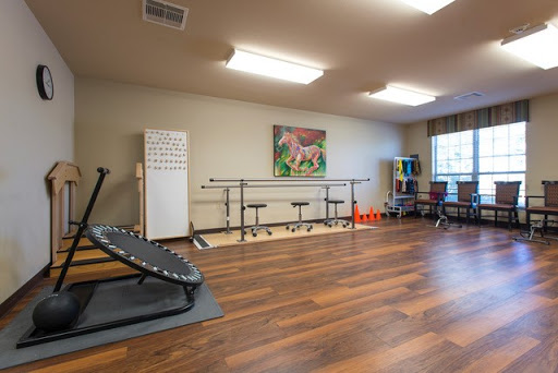 A spacious exercise and rehabilitation room equipped with a barre and fitness equipment.