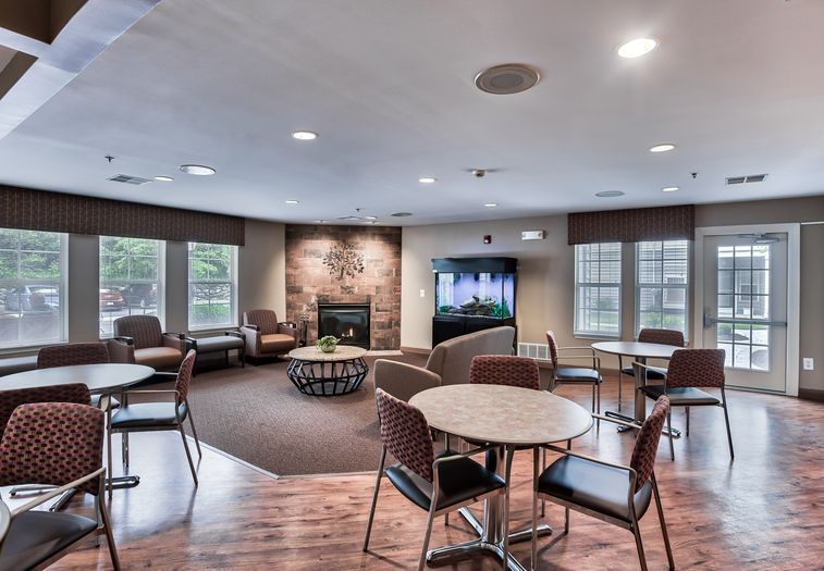 A cozy lounge area featuring a television, fireplace, and seating arrangements with tables and chairs.