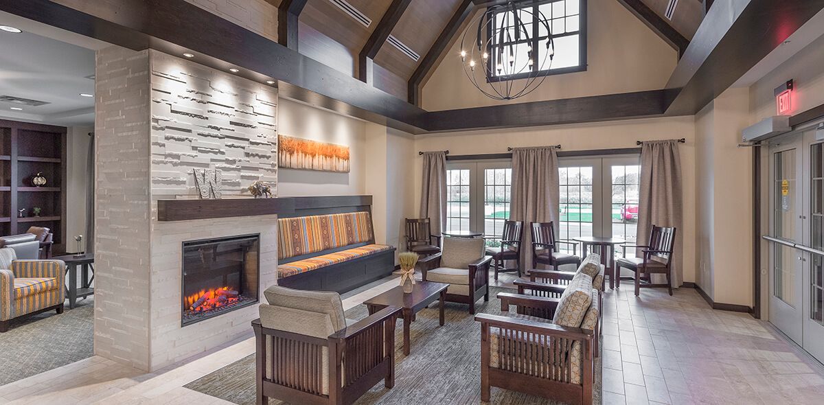 A modern living room with a cozy fireplace and high ceilings, featuring wooden beams and comfortable seating.