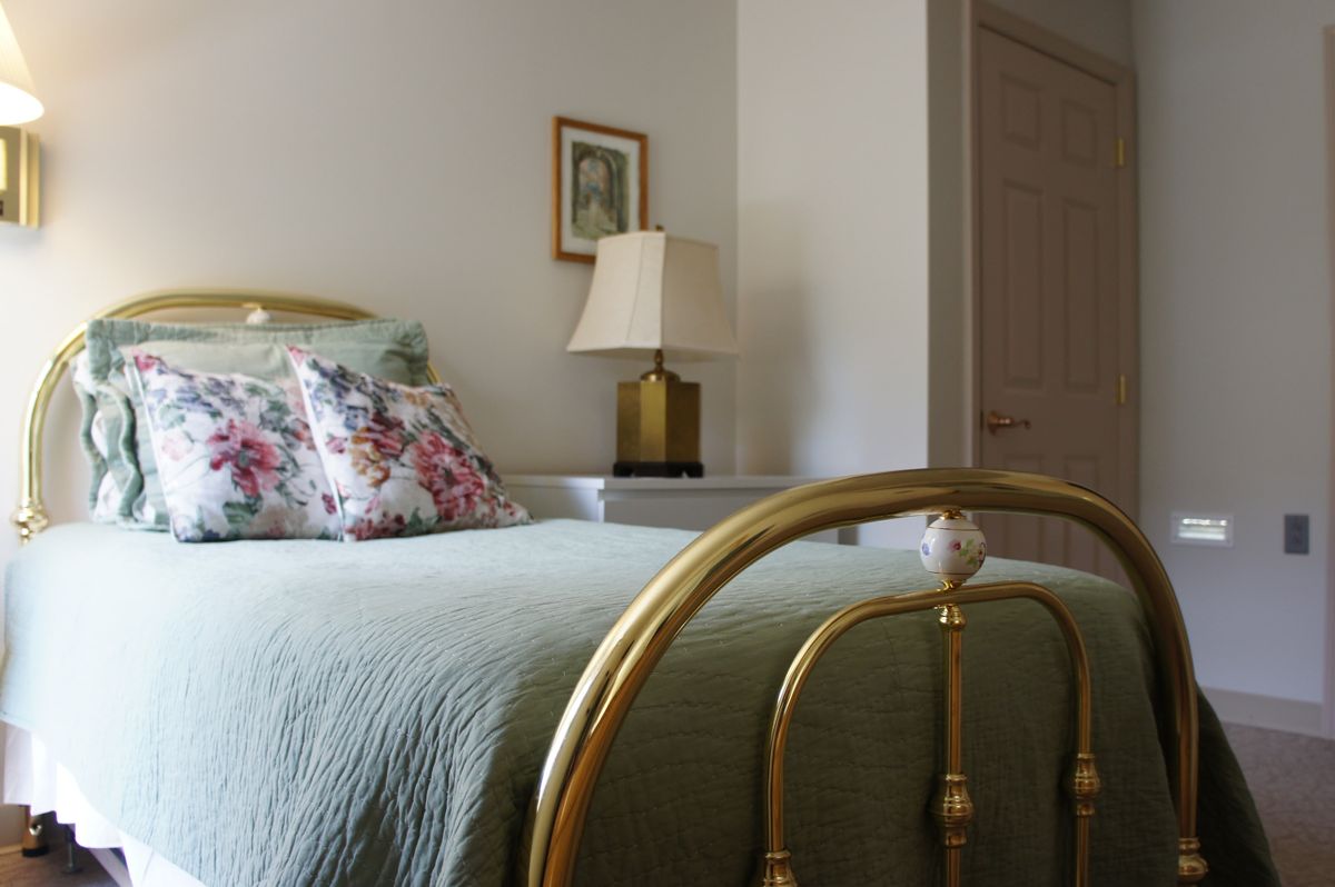 A cozy bedroom with floral pillows and a vintage brass bed frame.