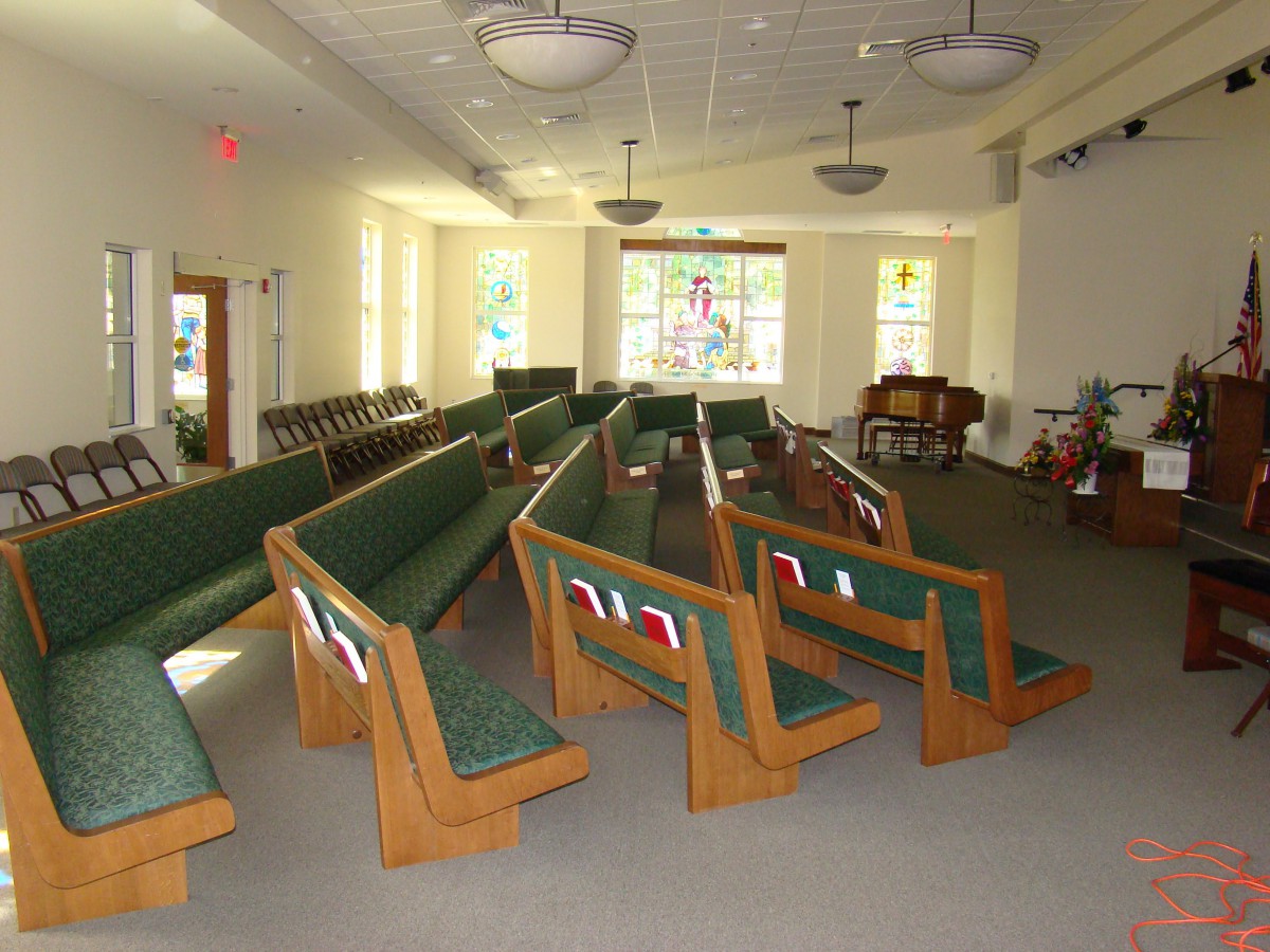 Interior view of a church with wooden pews and stained glass windows.