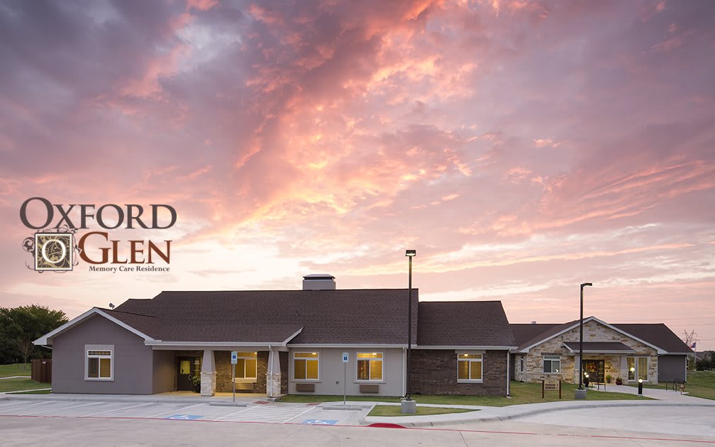 A residential building set against a vibrant sunset sky with scattered clouds.