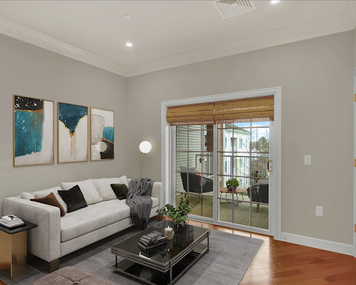 A cozy and modern living room featuring a stylish white sofa, contemporary artwork, and abundant natural light from large windows.
