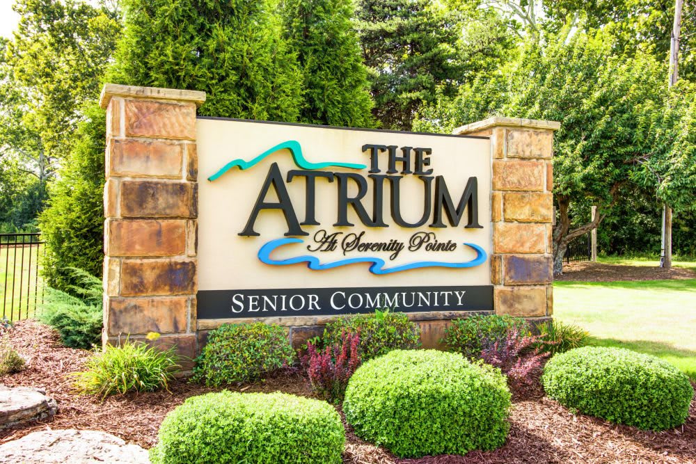 Entrance sign for The Atrium Senior Community surrounded by landscaped greenery.