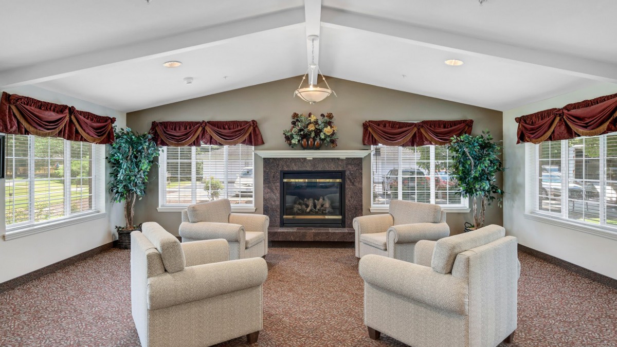 A cozy lounge area featuring comfortable armchairs arranged around a fireplace.