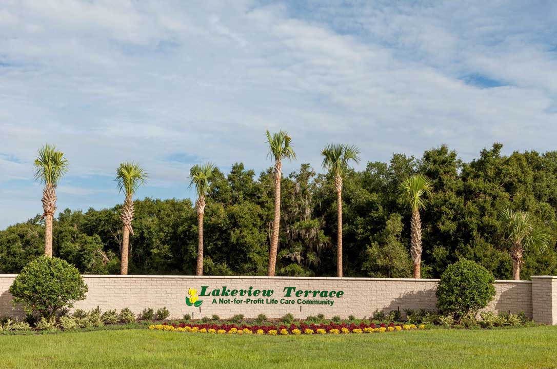 Entrance sign for Lakeside Terrace with palm trees and greenery.