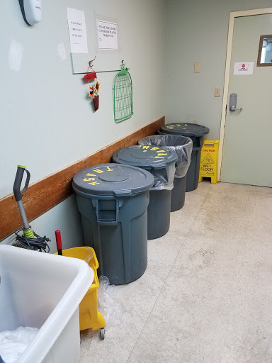A utility area featuring multiple garbage cans and cleaning supplies.