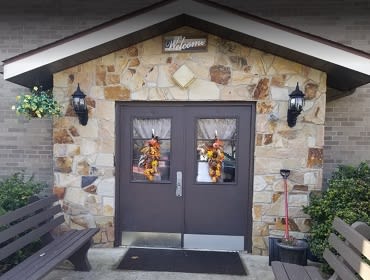 A welcoming entrance with stone walls and autumn-themed decorations on double doors.